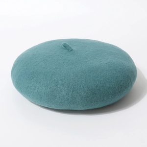 Detail van de groenblauwe wollen vilten baret met klassiek steeltje op witte basis