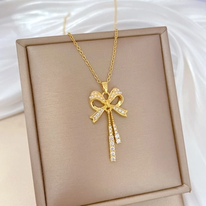 Macro shot of gold bow pendant with rhinestones and pearls on a silk background