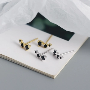 Macro shot of geometric S925 silver earrings with black zircon stones in gold and silver