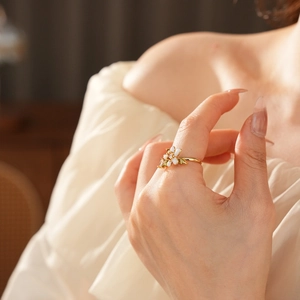 Primo piano di un anello a fiore placcato oro con petali in smalto e pietre verdi