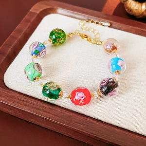 Close-up of vibrant glass beads with gold foil accents and elegant chain detail