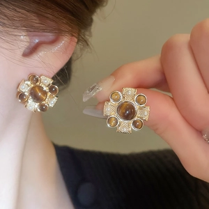 Macro detail of vintage floral pearl stud earrings with brown gemstone on model