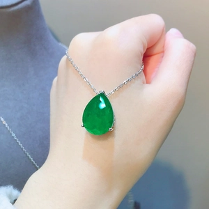 Close-up of elegant pear-shaped emerald green pendant necklace on silver chain
