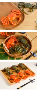 Detailed view of realistic PVC crab models in orange and green on a bamboo tray