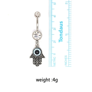 Macro shot of a Hamsa hand belly ring with evil eye charm, measuring 5cm in length
