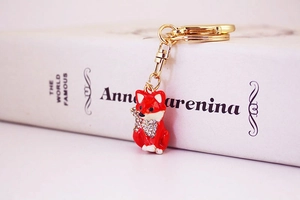 Detail of a red fox keychain with sparkling crystals and gold-plated hardware on a white book
