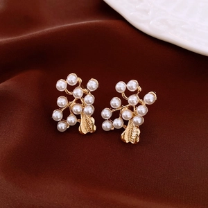 Detailed close-up of gold flower earrings with white pearls on a brown satin fabric