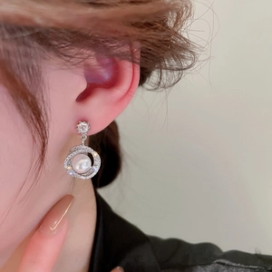 Close-up of model wearing silver flower pearl earrings with sparkling zircon accents