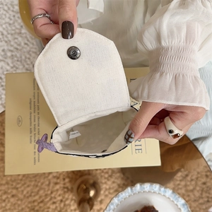 Close-up of portable canvas mini pouch featuring snap button and purple drawstring