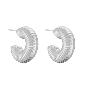 Macro detail of silver C-shaped hoop earrings with textured spiral geometric patterns