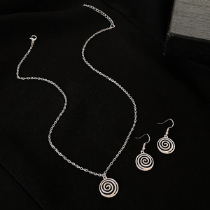 Détail macro du collier pendentif et boucles d'oreilles spirale en argent sur fond noir