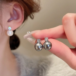 Macro detail of elegant pearl earrings with zircon inlay showing white and grey luster