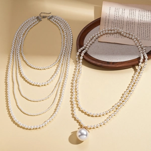 Baroque style layered faux pearl necklaces with a golden pendant on vintage book pages
