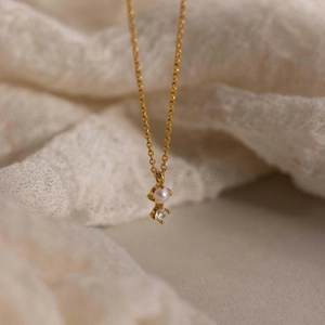 Macro shot of gold titanium necklace with white pearl and zircon against lace