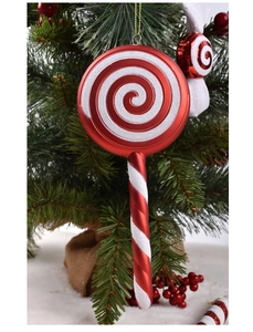 Close-up of a red and white glitter candy cane ornament hanging on a green Christmas tree