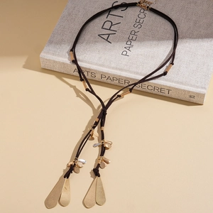 Détail d'un long collier à pompon vintage avec cordon marron et pendentifs feuilles dorées