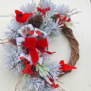 Detail of Christmas wreath with red cardinal birds, pine cones, and velvet bow on door