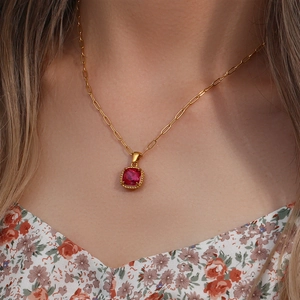 Macro shot of a red square gemstone pendant on a gold paperclip chain necklace