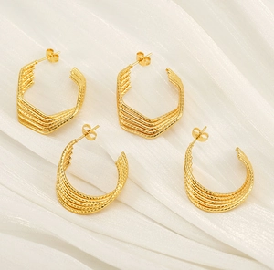 Detail showing gold plated geometric U-shaped and multi-layered C-ring earrings with texture