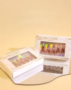 Détail de faux ongles Y2K ambre marron avec motifs blancs dans un emballage de luxe
