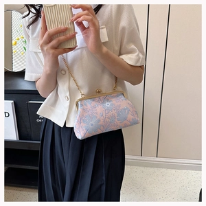 Detail of vintage kiss-lock clutch with floral jacquard and golden chain strap