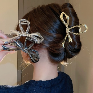 Trois pinces à cheveux noeud en or, argent et anthracite portées par un mannequin