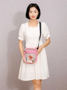 Detail of pink transparent PVC crossbody bag with adjustable strap and cosmetic contents