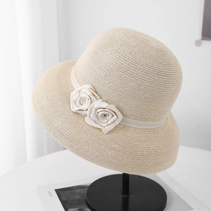 Détail d'un chapeau en paille beige avec roses en tissu et texture de tissage fine