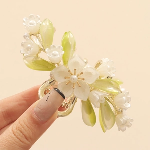 Close-up of white camellia hair claw with lily of the valley tassels and pearls