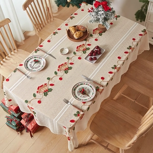 Close-up of festive beige Christmas tablecloth with red bell embroidery and lace detail