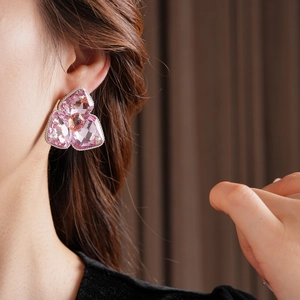 Close-up of pink crystal flower earrings with intricate metal inlay on model