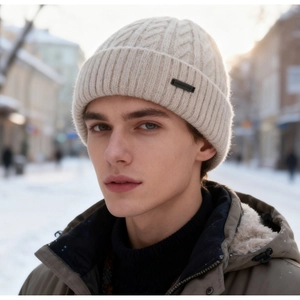Detail of cream rib-knit beanie with leather patch in a snowy outdoor setting