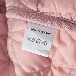 Detail of pink quilted polyester jacket with wash care label and stitch pattern