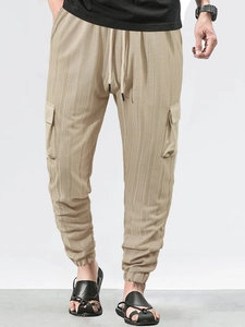 Detail of khaki cargo pants featuring vertical stripe texture and large side pockets