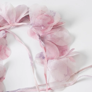 Detail van de roze organza bloemen met kleurverloop en stiksels op de jurk