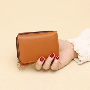 Brown faux leather short wallet with fine stitching and metal zipper in hand