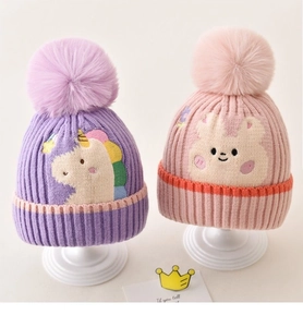 Detail of pink and purple knitted baby hats with plush pom-poms and cartoon embroidery