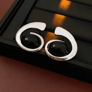 Silver geometric swirl earrings with black oval gemstones on a luxury display