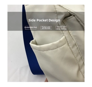 Detail shot of the cream crossbody bag showing a side pocket and blue textile strap