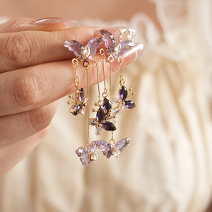 Gros plan de boucles d'oreilles papillon dorées avec cristaux violets et clairs
