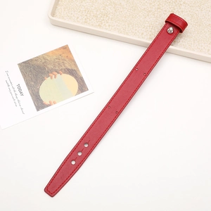 Detail of red textured leather wrist strap with silver metal screw and stitching accents