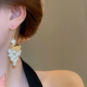 Detail view of grape-shaped tassel earrings featuring white pearls and golden leaves