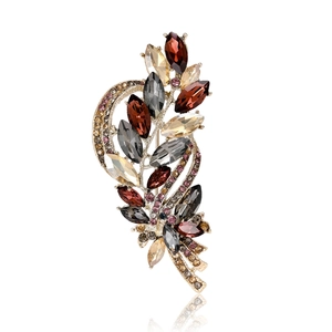 Elegant wheat stalk brooch with colorful crystals in a golden alloy setting on white
