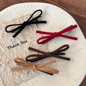 Detailed set of four velvet bow hair clips in red, black, and brown on a ceramic tray