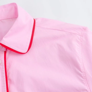 Dettaglio della maglia rosa a maniche corte con bordo rosso e trama in cotone