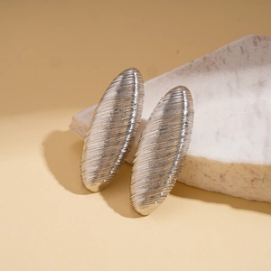 Macro view of silver geometric oval earrings featuring textured brushed metal finish