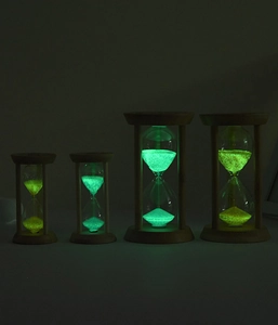 Glow-in-the-dark sand timers with wooden base and luminous powder in dark setting