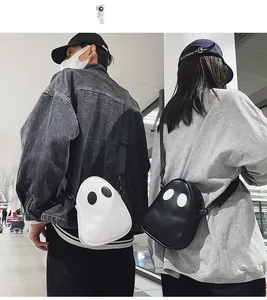 Detail of cute ghost-shaped PU leather crossbody bags in black and white worn by couple