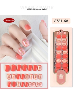 Detail of coral pink square press-on nails with golden floral patterns and retail box
