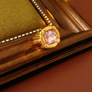 Dettaglio di anello vintage con zircone rosa quadrato e fascia dorata su legno